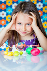 Cute little girl painting Easter eggs