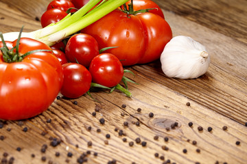 Red tomatoes with pepper and garlic on old wooden table