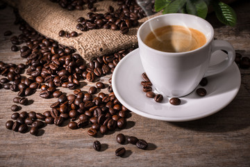 Cup of coffee and coffee beans on wooden background