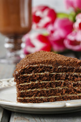 Piece of chocolate layer cake and irish coffee on wooden table.