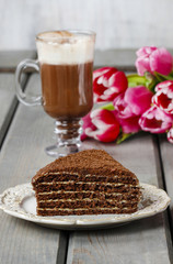 Piece of chocolate layer cake and irish coffee on wooden table.