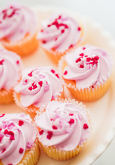 Cupcakes with pink cream and heart sprinkles