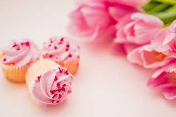 Obraz na płótnie Canvas Cupcakes with pink cream,heart sprinkles and tulips on white tab