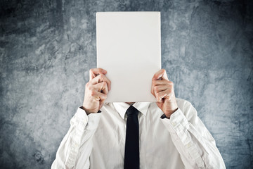Businessman holding blank paper in front of his face