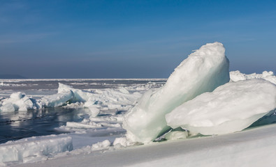 Frozen sea view on sunny day. Selective focus on ice rock.