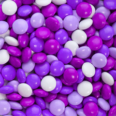 Chocolate candy coated in purple and white. Background