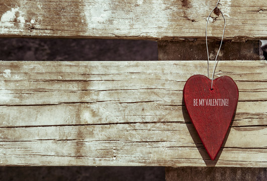 heart hanging on wooden background with text be my valentine