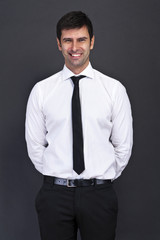 businessman standing on grey background with hands on back