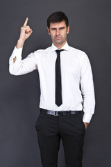 Young businessman criticizing on gray background