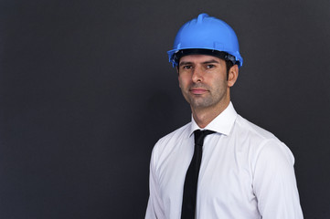 Young construction worker in hard hat on gray background