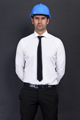 Young construction worker in hard hat on gray background