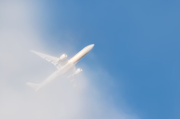 Fototapeta na wymiar passenger jet punching through cloud into blue sky