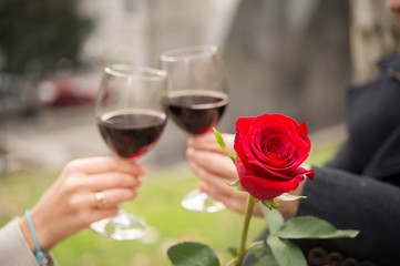 close up a single rose with a coule drinking wine