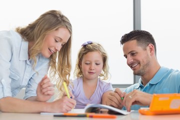 Fototapeta premium Parents assisting daughter in drawing at table
