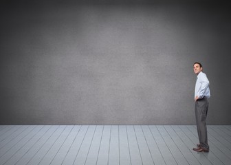 Composite image of smiling businessman with hand on hip