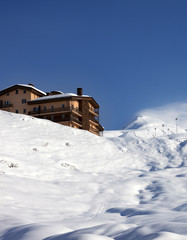 Off-piste slope and hotel at sun day