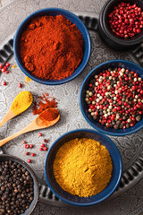 Fototapeta premium spices in bowls: curry pink and black pepper paprika powder