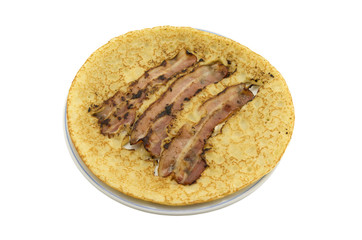 A plate with a pancake with bacon strips on a white background.