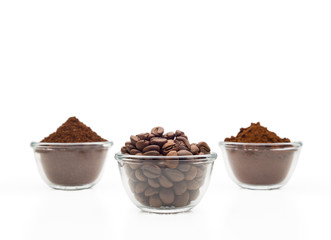 Coffee beans, ground coffee and instant coffee, in little glass cups on a clean white background