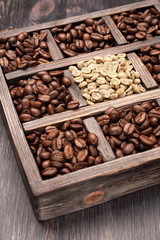 Green unroasted and brown coffee beans in old wooden box