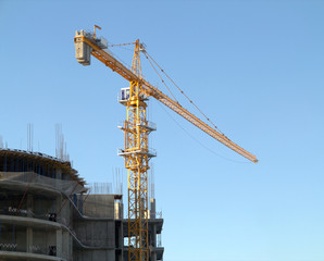 Yellow hoisting tower crane in construction process
