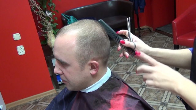 Barber cutting hair with scissors comb