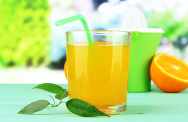 Citrus press, glass of juice and ripe orange
