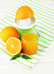 Citrus press, glass of juice and ripe oranges
