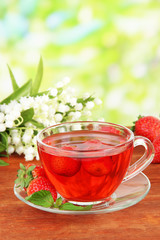 Delicious strawberry tea on table on bright background