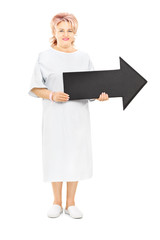 Female patient in hospital gown holding big black arrow