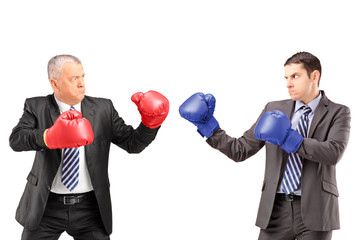 Mature businessman with boxing gloves ready to fight his coworke