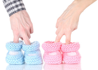 Hands with crocheted booties for baby, isolated on white