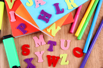 English alphabet, books and markers on wooden background