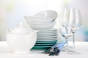 Clean dishes on table on bright background