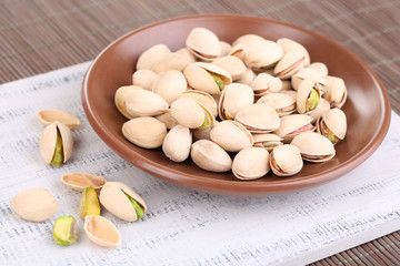 Pistachio nuts on plate on wooden background