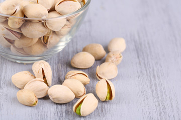 Pistachio nuts in glass bowl on wooden background