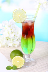 Glass of cocktail on table on light blue background