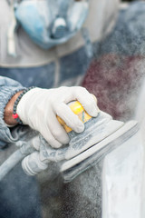 Young auto mechanic using the power buffer machine for painting