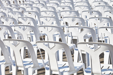 rear view white plastic chair rows outdoor concrete yard