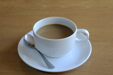 White coffee-cup with spoon on wooden table