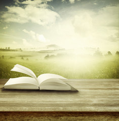 Open book on table and spring scene