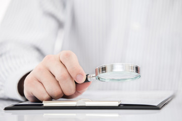 Businessman looking through a magnifying glass