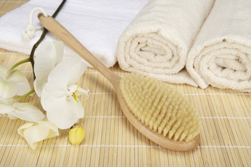 Fototapeta na wymiar Badebürste, Handtücher und Orchidee auf Bambusmatte