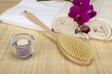 Badebürste, Handtücher und Orchidee auf Bambusmatte