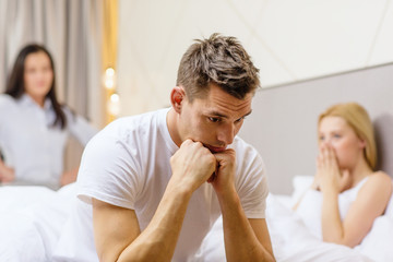 man sitting on the bed with two women on the back