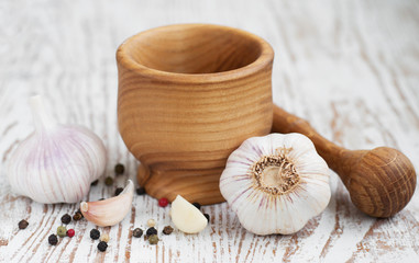 Garlic  with mortar and pestle on a wooden  background.