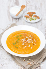 carrot soup with almonds and watercress on white wooden table