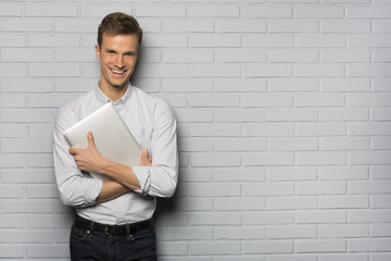 Handsome Cheerful man holding a laptop, isolated over a wall - obrazy, fototapety, plakaty