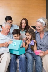 Extended family sitting on sofa with gift boxes in living room