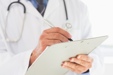 Doctor writing on clipboard